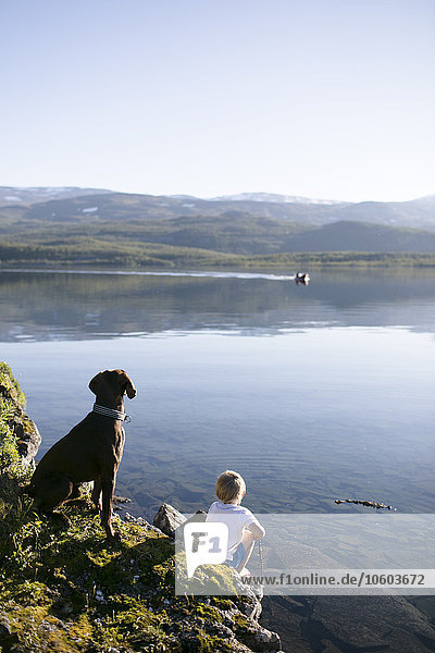 Boy with dog sitting on coast