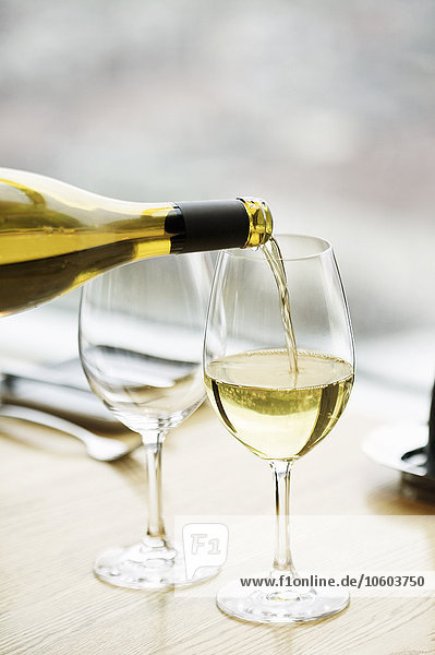 Weißwein wird in ein Weinglas gegossen