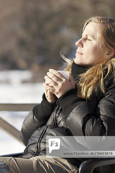 Woman having coffee on bench