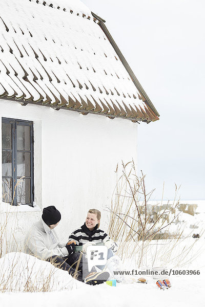 Paar sitzt in der Nähe von Haus im Winter