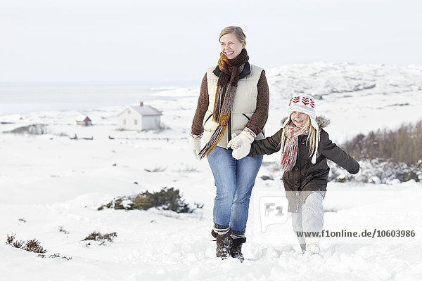 Frau geht mit Tochter im Winter spazieren