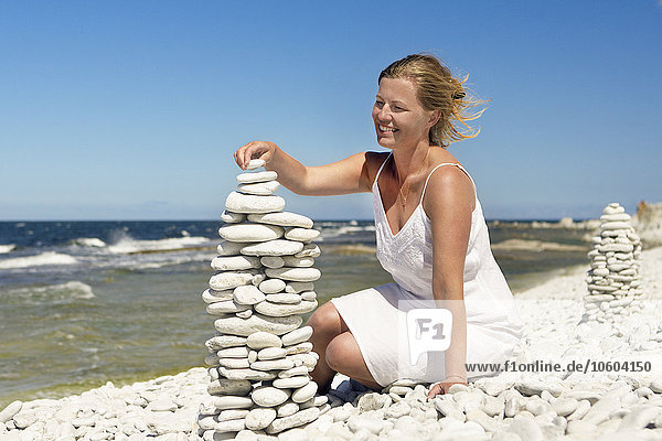 Woman on beach stacking stones
