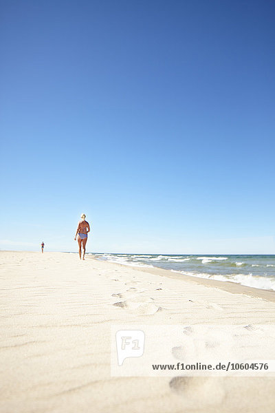 Frau geht am Sandstrand spazieren