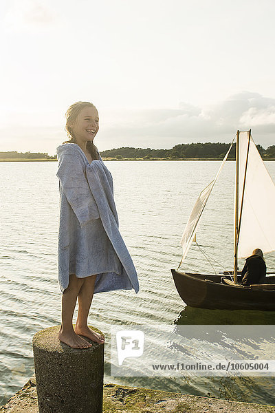 Smiling girl wrapped in blanket at sea