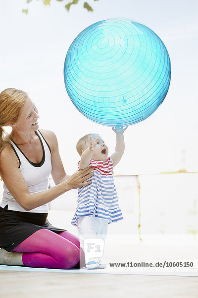 Mother with baby girl playing fitness ball