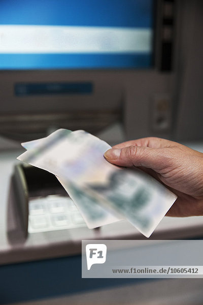 Hand  die Geld von Geldautomaten nimmt