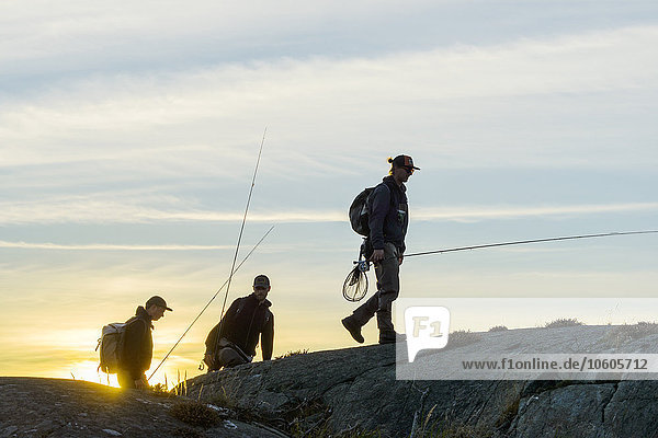 Men with fishing rods walking on coast