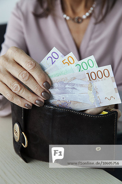 Frau steckt schwedische Kronen in ihre Brieftasche