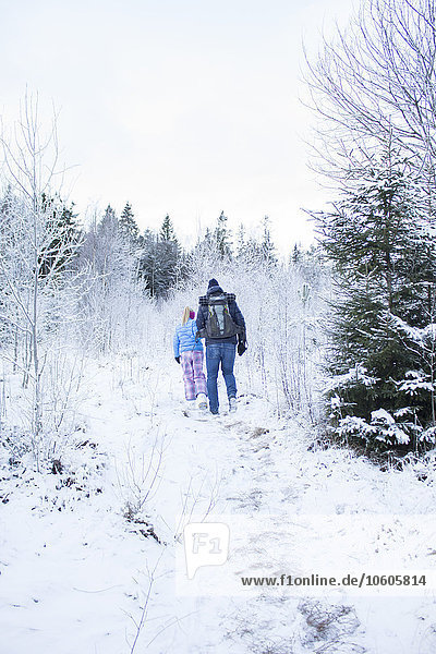 Rear view of two people walking in winter forest