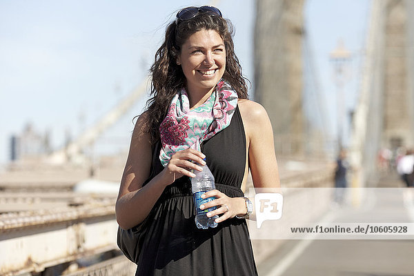 Woman holding water bottle with Brooklyn Bridge in background