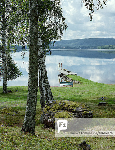 A bridal couple standing by a lake  Sweden.
