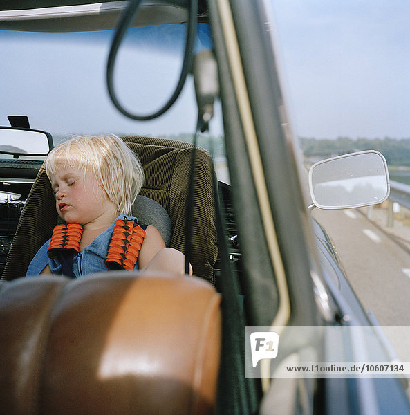 Ein Mädchen schläft auf einem Sicherheitssitz im Auto  Schweden.
