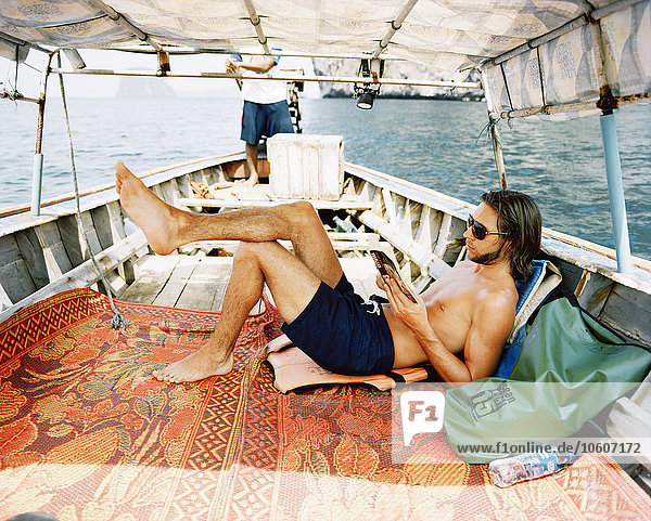 Ein skandinavischer Mann liest auf einer Bootsfahrt ein Buch.