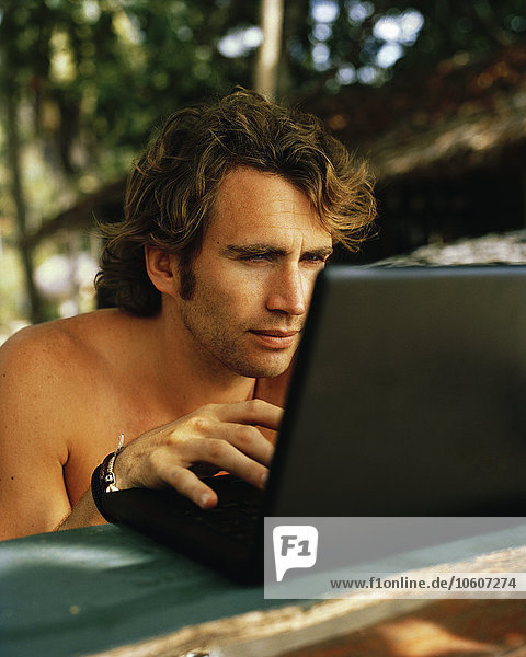 Ein Mann benutzt während seines Urlaubs einen Laptop.
