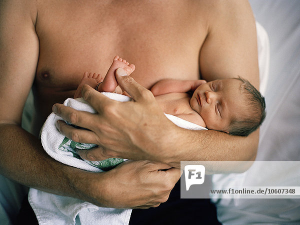 A newborn baby in the arms of a man  Sweden.