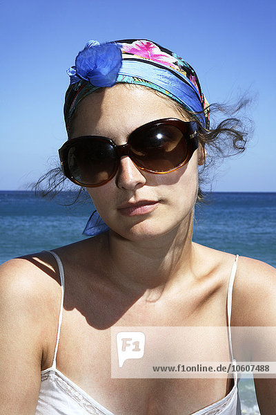 Junge Frau mit Sonnenbrille am Meer sitzend  Griechenland.