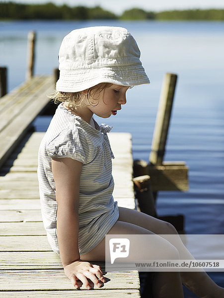Ein kleines Mädchen auf einem Steg an einem See  Schweden.