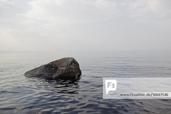 Ein einzelner Stein in einem nebelumhüllten See  Schweden.