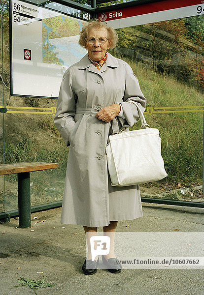 Eine ältere Frau an der Bushaltestelle