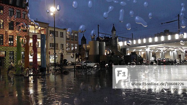 Regentropfen auf Fenster im Regen mit Straßenszene im Hintergrund in der Nacht