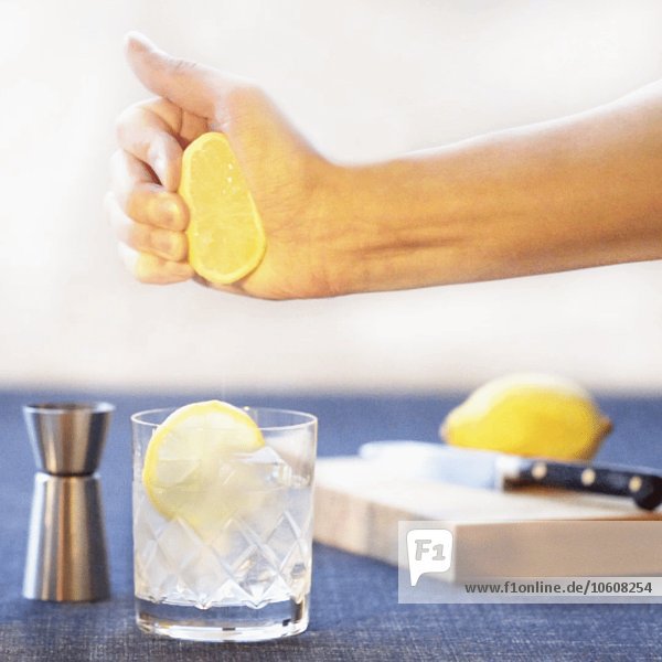 Zitrone von Hand in Cocktail pressen