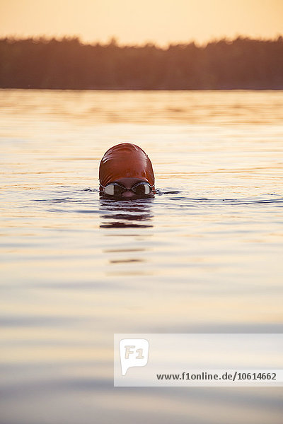 Person swimming at sunset