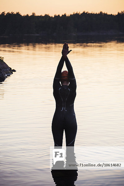 Swimmer standing in water at sunset