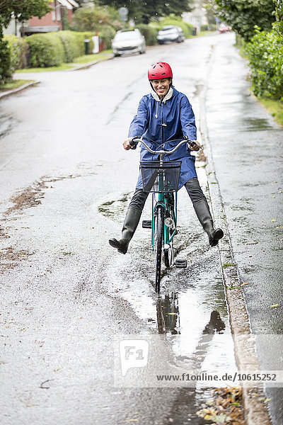 Woman riding bicycle through puddle