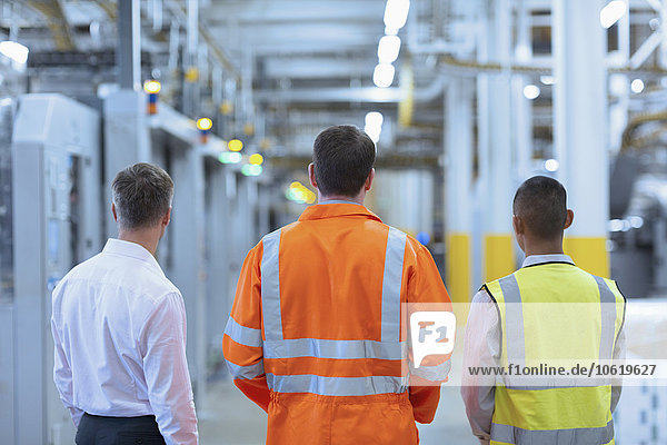 Arbeiter und Aufseher stehen im Fabrikkorridor