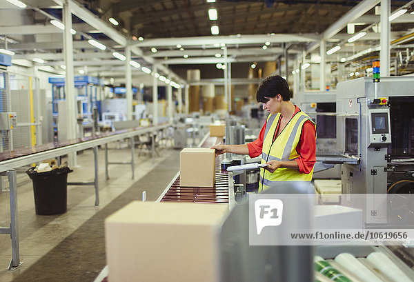 Worker checking cardboard boxes on conveyor belt production line in factory