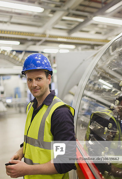 Portrait confident worker leaning on machinery in factory