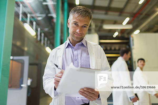 Portrait confident scientist with clipboard in factory