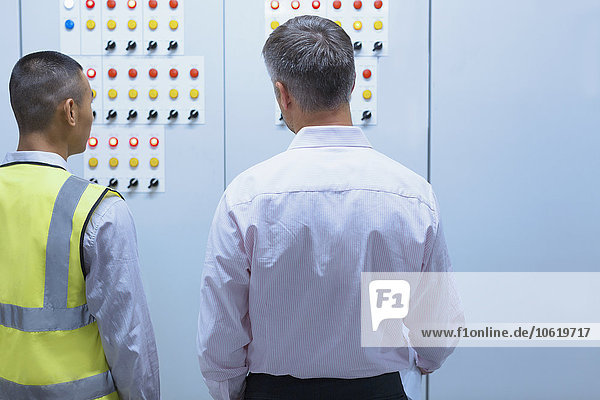 Supervisor und Mitarbeiter am Schaltschrank in der Fabrik