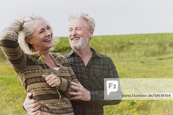 Smiling senior couple hugging in field