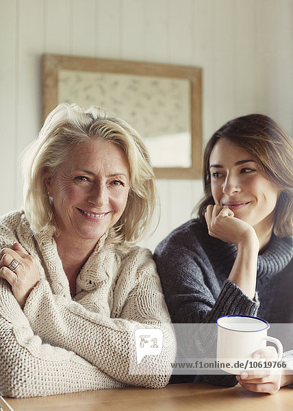 Portrait smiling mother and daughter in sweaters drinking coffee