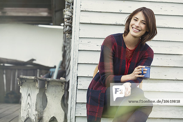 Portrait lächelnde brünette Frau beim Kaffeetrinken auf der Veranda