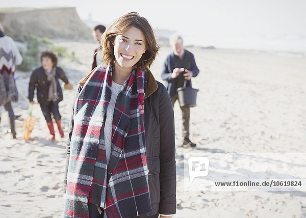 Portrait smiling woman in plaid scarf with family on beach