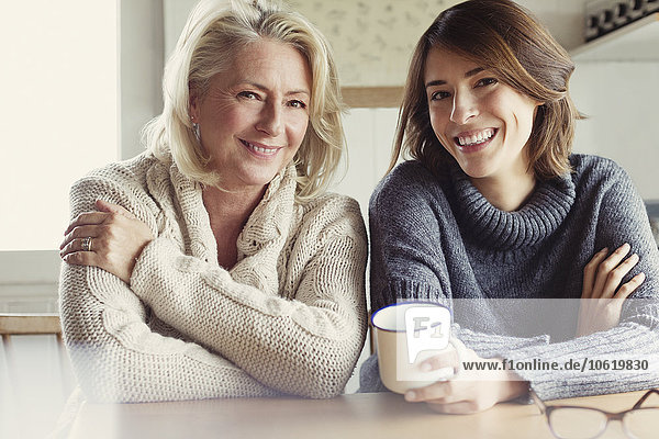 Portrait lächelnde Mutter und Tochter in Pullovern beim Kaffeetrinken in der Küche