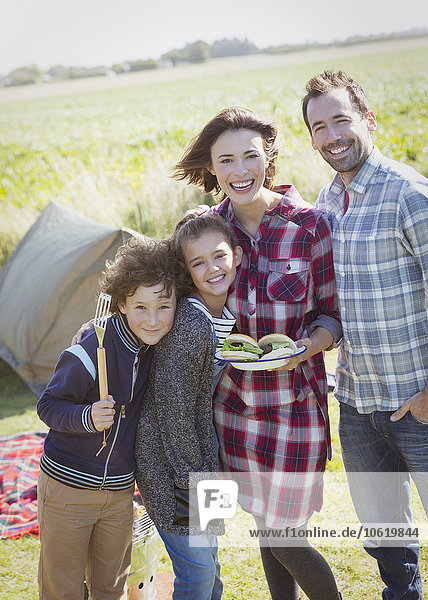 Portrait lächelnde Familie mit gegrillten Hamburgern auf dem sonnigen Campingplatz