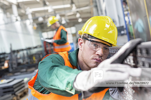 Fokussierter Arbeiter beim Prüfen von Stahlteilen in der Fabrik