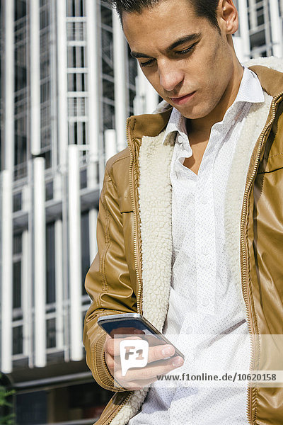 Young man with a leather jacket using his cell phone