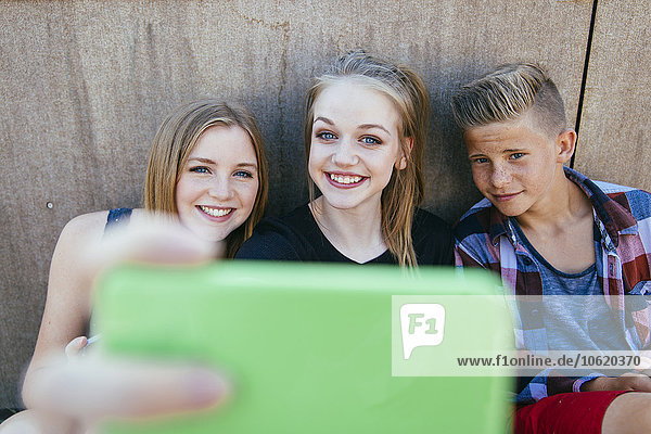 Drei Teenager im Freien mit einem Selfie.