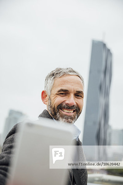 Österreich  Wien  Geschäftsmann  der mit seinem Smartphone einen Selfie vor DC Towers nimmt.
