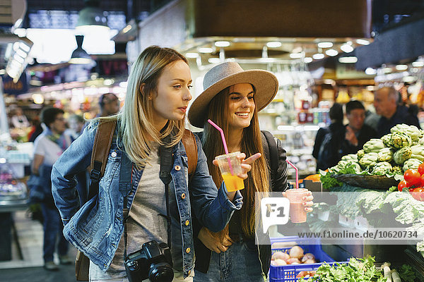 Zwei junge Frauen trinken Smoothies auf dem Markt