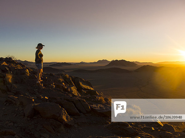Afrika  Namibia  Hardap  Hammerstein  Kulala Wilderness Reserve  Tsaris-Gebirge  Frau steht bei Sonnenuntergang in der Namib-Wüste