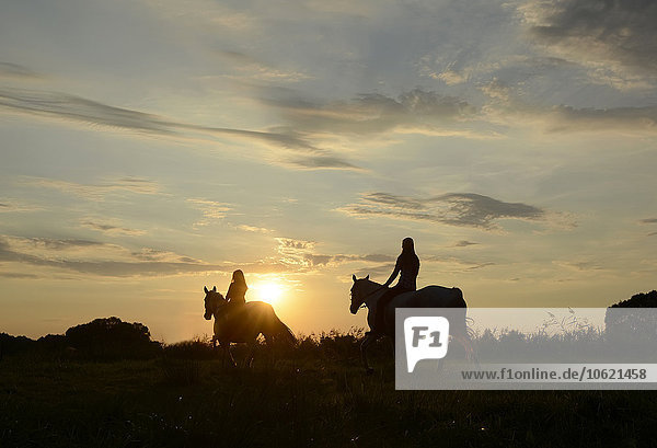 Junge Frauen reiten in den Sonnenuntergang
