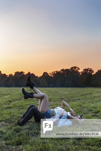 Glückliches verliebtes Paar liegt bei Sonnenuntergang auf einer Wiese.
