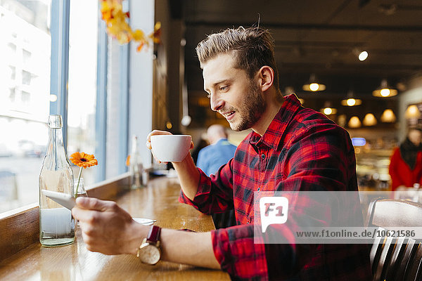 Mann in einem Coffee-Shop mit Blick auf digitales Tablett