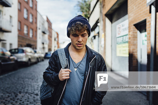 Irland  Dublin  junger Mann  der mit einem Rucksack auf der Straße geht.