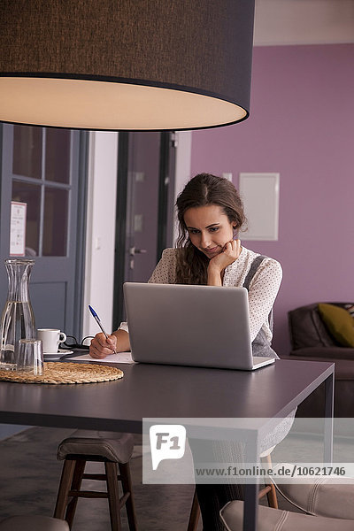 Young woman sitting at table using laptop